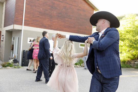 Flower girl dancing with father in cowboy hat at wedding reception