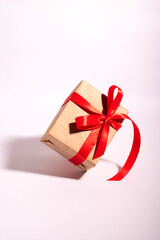 A gift in a kraft paper with red ribbon on a white background