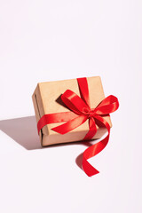 A gift in a kraft paper with red ribbon on a white background