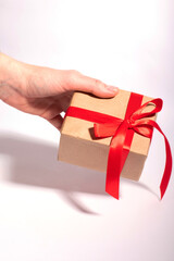 A gift with a red ribbon in woman's hands on a white background