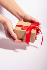 A gift with a red ribbon in woman's hands on a white background