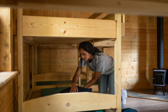 Girl making bed in cabin at summer camp