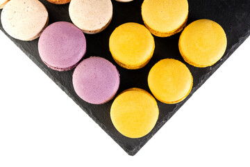 Macarons are laid out on a black slate in beautifully colored rows.