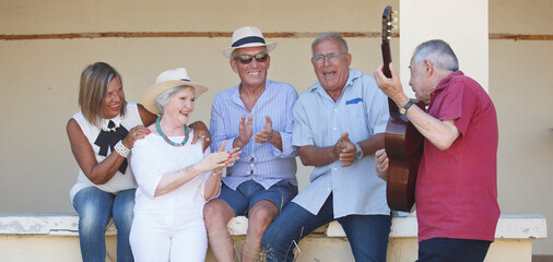 Gruppo di anziani vitali canta e suona con la chitarra una canzone seduti in una panchina