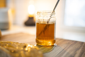 Honey jar and a slice of bread with peanut butter on wooden table