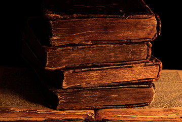 Stack of old shabby Jewish books in leather binding on the open pages of Machzor in the dark....
