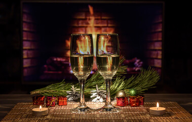 Two glasses with wine on the table against the background of the fireplace. Christmas New Year decorations, fireplace.