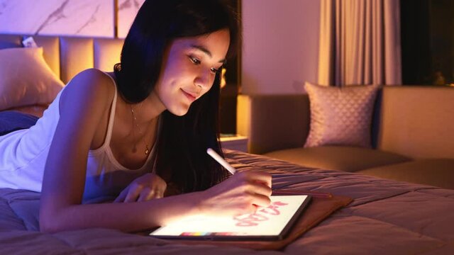 Young Asian beautiful sexy woman  using smartphone- tablet  enjoy  social online and facetime and listening music on bed with happy and smile in bedroom at night time.