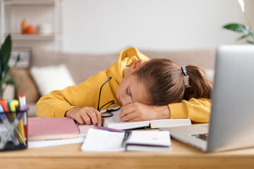 Exhausted school girl sleeping at desk while doing lots of homework, getting ready before exams,...