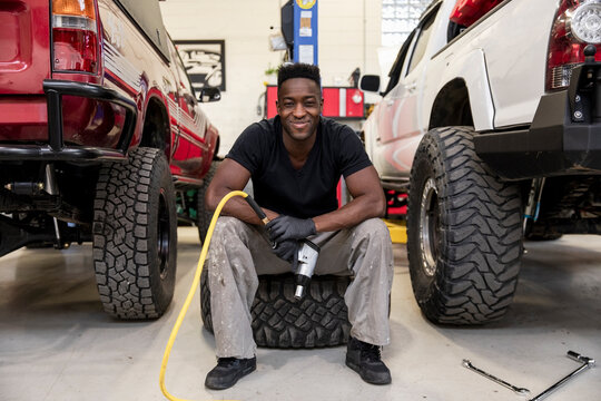 Portrait Happy Confident Male Auto Mechanic Changing SUV Tires