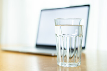 Drinking water in a glass left on the table in office, work life balance concept with copyspace. 