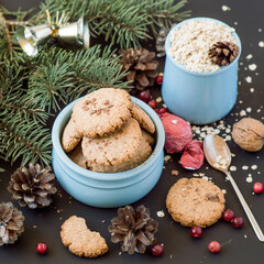 Preparing for Christmas. Homemade oatmeal cookies, green spruce branch and pine cones on a dark background. Selective focus.