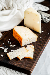 Delicious Dutch gouda cheese with cheese blocks on an old wooden white table. Piece of cheese on a dark board