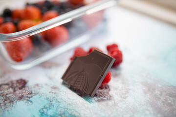 Bitten chocolate bar and raspberries on a colorful placemat