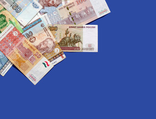 Photo of somoni bank notes from Tajikistan and Russian ruble bank notes on blue background. 