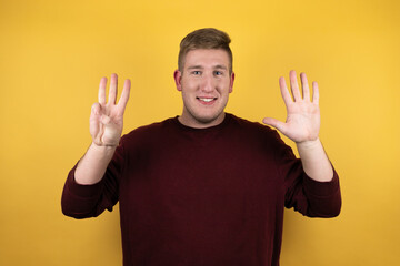 Fototapeta premium Young blonde man wearing a casual red sweater over yellow background smiling confident and happy showing number eight with fingers