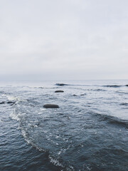 Fototapeta na wymiar Sea view with small waves and cloudy gray sky