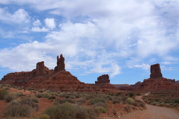 Large sandstone cliffs and colorful bright red wide plateaus make up the western Utah landscape; Valley of the Gods