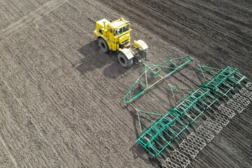 Early spring harrowing of the field with a tractor. Shooting from a drone. Copy space.