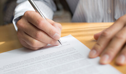 A man's hand signing a letter.  agreement. contract. writing a document.