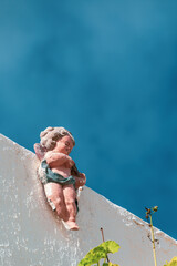 Little angel figure decorating a wall with the sky in the background.