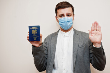 European man in formal wear and face mask, show Armenia passport with stop sign hand. Coronavirus lockdown in Europe country concept.