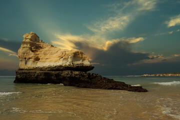 huge stone figured stone in the water near the ocean shore against the backdrop of the picturesque...
