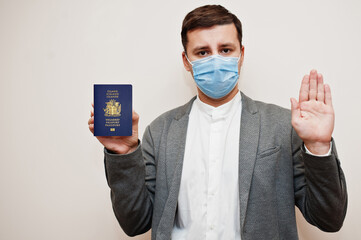 European man in formal wear and face mask, show Iceland passport with stop sign hand. Coronavirus lockdown in Europe country concept.