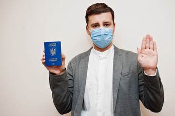 European man in formal wear and face mask, show Ukraine passport with stop sign hand. Coronavirus...