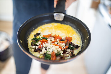 Mushroom, tomato and cheese omelette on a frying pan
