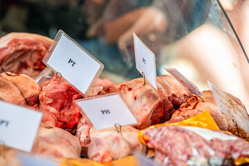 Butcher store shop window retail freezer display of pork meat chunks of tenderloin and ham tied with twine string rope in Chelsea food outdoor market in London, United Kingdom