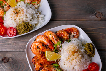 selected focus a plate of fried shrimp and white rice with pesto sauce on a brown wooden table