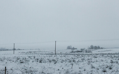 Country side meadow field covered with snow, first winter snow, frozen ground, grey color sky