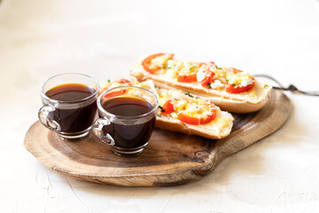 Cups of coffee and Two toasts with cheese, tomatoes and basil