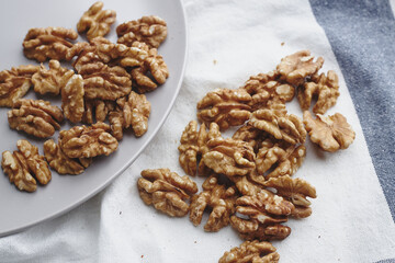 walnut kernels on a white blue tablecloth, craft paper and a gray round plate. ripe walnut fruit for vegenans