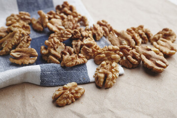 walnut kernels on a white blue tablecloth, craft paper and a gray round plate. ripe walnut fruit for vegenans