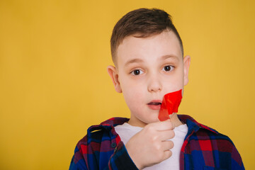 A nine-year-old boy with a mouth taped with red tape. The child is not allowed to speak.