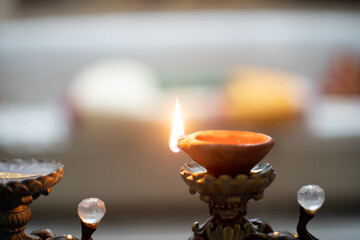 Panning shot of a diya placed indoors with out of focus background of a house and a strong flame burning on the hindu festival of diwali