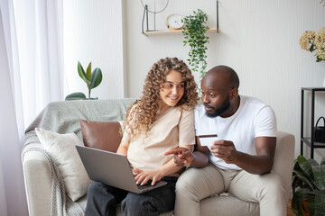 Happy future parents, resting at home on sofa, preparing for birth of daughter, buy the most necessary things and pay by card online. Family, happy and technology concept.