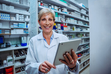 Caucasian senior pharmacist scrolling on digital tablet smiling standing in pharmacy