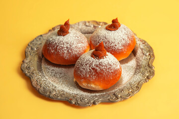 Hanukkah donuts on a vintage plate on a yellow background.