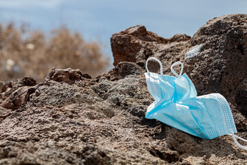 Surgical mask thrown away on a rock facing the sea