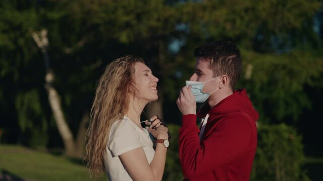 Young man and woman take off medical mask and kiss. Pandemic is over. Finally end of quarantine. Pretty couple date after long self isolation. Health care and medical concept. Happy people.
