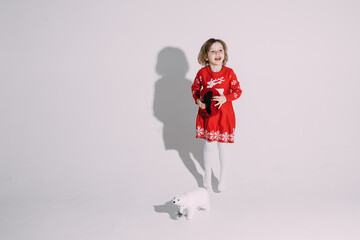 Fototapeta na wymiar pretty caucasian girl in red dress with a little white bear toy near her