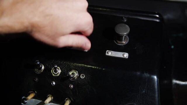 Vintage control panel with levers. Media. Close-up of man pressing shift levers on control panel of old device. Retro device with switches