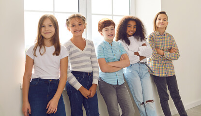 Smiling diverse children standing by the window at home or during break at school