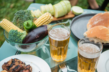 Beer, kebab, vegetables, grill, kebab spread out on the picnic table. A warm summer day and a trip to nature. Photo with no people
