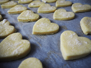 Fototapeta na wymiar lots of raw curd cookies sprinkled with sugar are laid out on parchment paper before baking side view . baking at home for Valentine's day, Valentine's day
