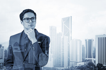Fototapeta premium Young handsome businessman in suit and glasses dreaming about new career opportunities after MBA graduation. Kuala Lumpur on background. Double exposure.