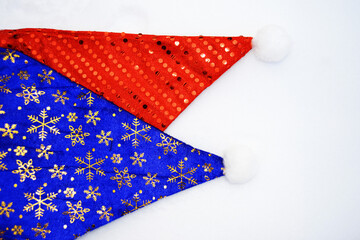 Red and blue Christmas hats on white snow